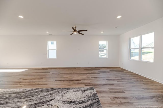 unfurnished room with plenty of natural light, recessed lighting, a ceiling fan, wood finished floors, and baseboards