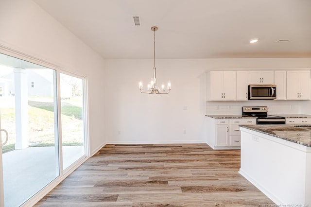 kitchen featuring appliances with stainless steel finishes, dark stone counters, light wood-style floors, a chandelier, and recessed lighting