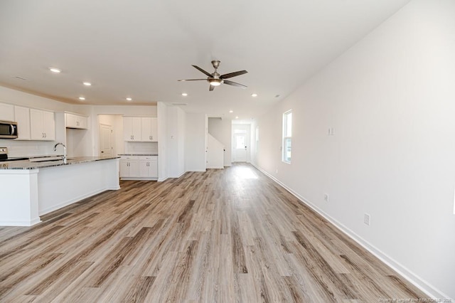 unfurnished living room with light wood-type flooring, recessed lighting, a ceiling fan, and baseboards