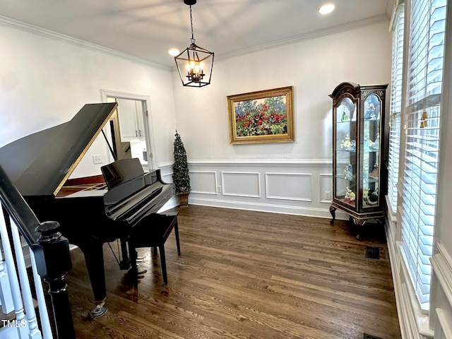 living area featuring crown molding, dark wood-type flooring, a chandelier, a wainscoted wall, and recessed lighting
