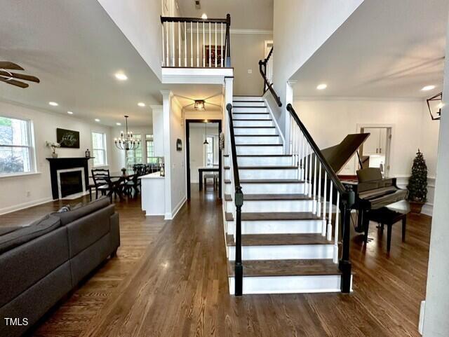 stairway with healthy amount of natural light, a ceiling fan, wood finished floors, ornamental molding, and recessed lighting