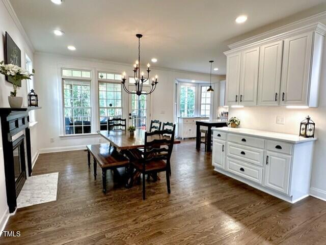 dining space featuring baseboards, a chandelier, crown molding, dark wood-style floors, and recessed lighting