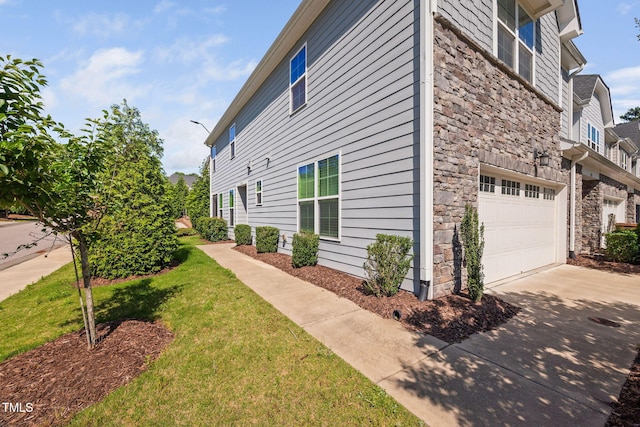 1103 Laurel Twist Rd, Cary, NC 27513 - view of side of home with stone siding, a garage, driveway, and a lawn