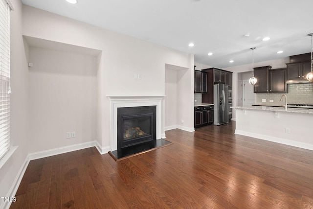 1103 Laurel Twist Rd, Cary, NC 27513 - unfurnished living room with recessed lighting, dark wood finished floors, a glass covered fireplace, a sink, and baseboards