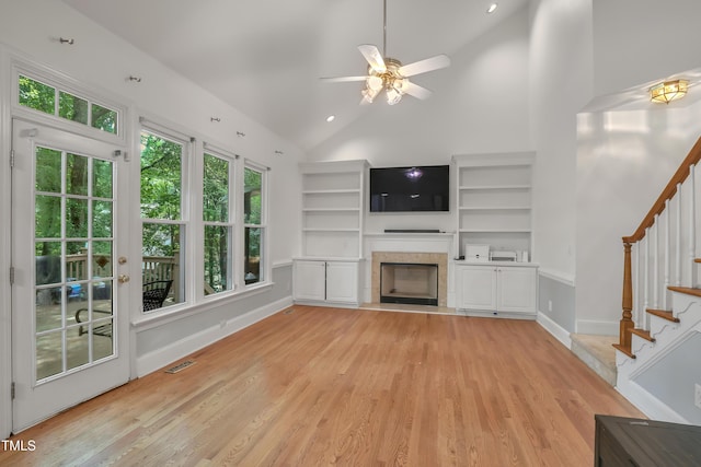 123 W Camden Forest Dr, Cary, NC 27518 - unfurnished living room with light wood-style floors, a tile fireplace, stairway, a ceiling fan, and high vaulted ceiling