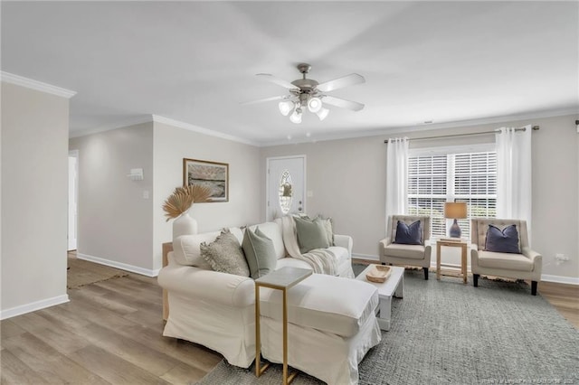 living room featuring baseboards, wood finished floors, a ceiling fan, crown molding, and plenty of natural light