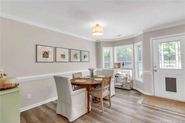 dining area featuring light wood-type flooring, plenty of natural light, baseboards, and crown molding