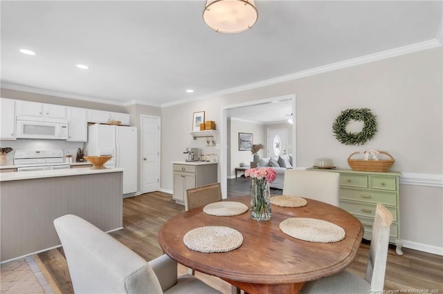 dining area with light wood-style floors, crown molding, recessed lighting, and baseboards