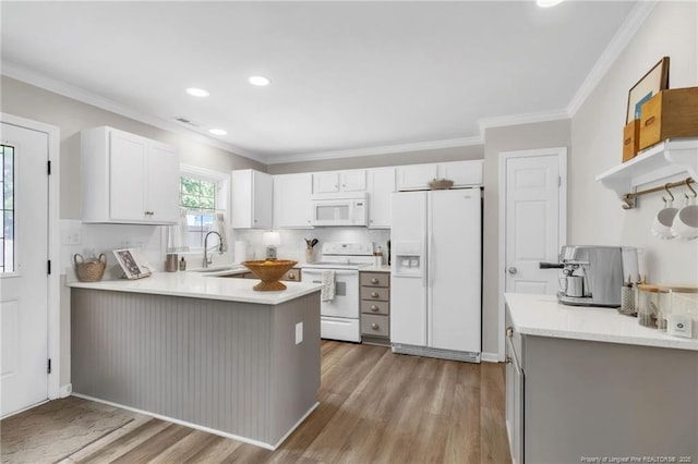 kitchen featuring white appliances, a peninsula, light wood-style floors, ornamental molding, and light countertops
