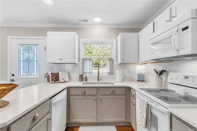 kitchen featuring white appliances, a sink, backsplash, gray cabinets, and ornamental molding