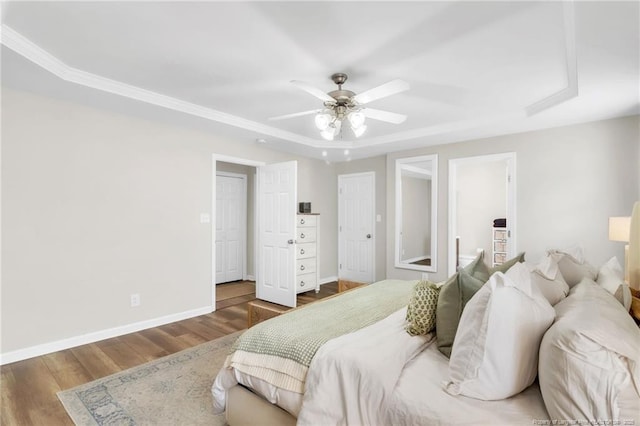 bedroom with wood finished floors, baseboards, a ceiling fan, and a raised ceiling