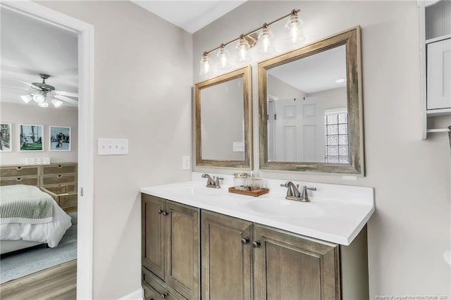 ensuite bathroom with a ceiling fan, baseboards, double vanity, and wood finished floors