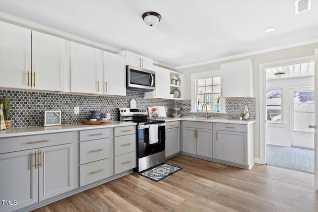 201 Van St, Pinetops, NC 27864 - kitchen featuring appliances with stainless steel finishes, gray cabinets, backsplash, light wood-style flooring, and crown molding