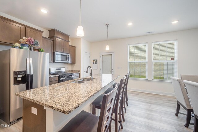 113 Blandford St, Franklinton, NC 27525 - kitchen with appliances with stainless steel finishes, a sink, a breakfast bar, a kitchen island with sink, and light wood-type flooring