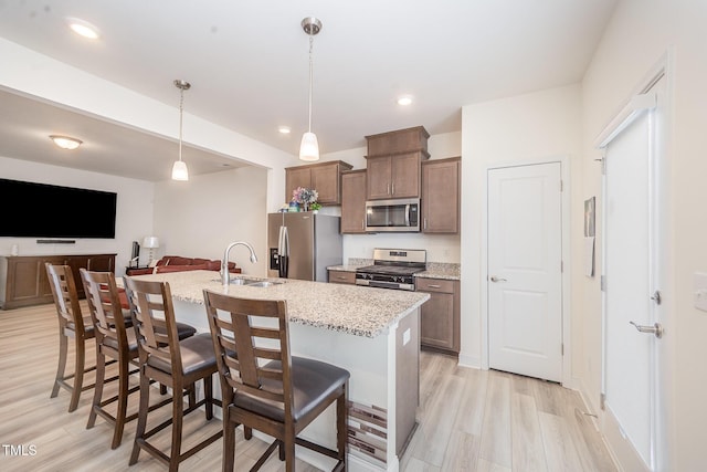 113 Blandford St, Franklinton, NC 27525 - kitchen featuring appliances with stainless steel finishes, a sink, light wood-style floors, a breakfast bar area, and a center island with sink