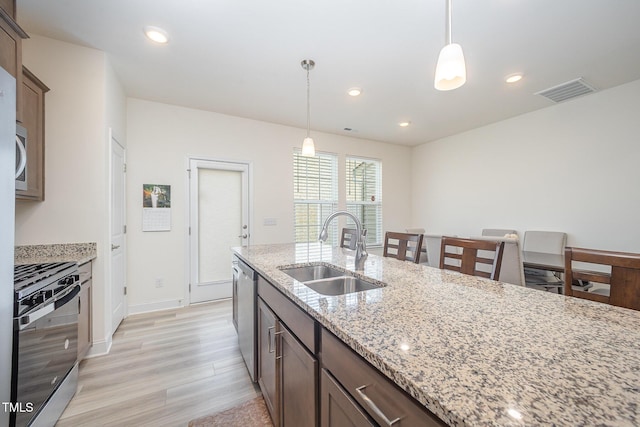 113 Blandford St, Franklinton, NC 27525 - kitchen featuring a sink, range with gas stovetop, light wood finished floors, dishwasher, and decorative light fixtures
