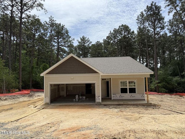view of front of property featuring an attached garage, a porch, and dirt driveway