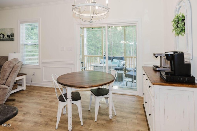 176 Lowery Ln, Benson, NC 27504 - dining area with a chandelier, crown molding, light wood-style flooring, a wainscoted wall, and a decorative wall