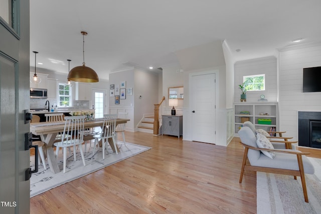 3003 University Dr, Durham, NC 27707 - dining area featuring light wood-style flooring, stairs, a fireplace, ornamental molding, and a decorative wall