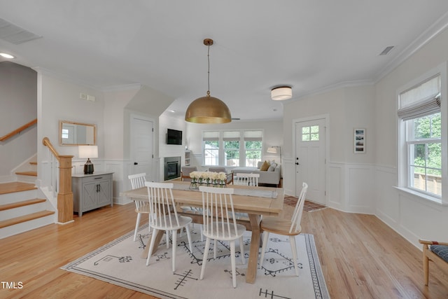 3003 University Dr, Durham, NC 27707 - dining area with a glass covered fireplace, stairway, light wood-type flooring, wainscoting, and crown molding
