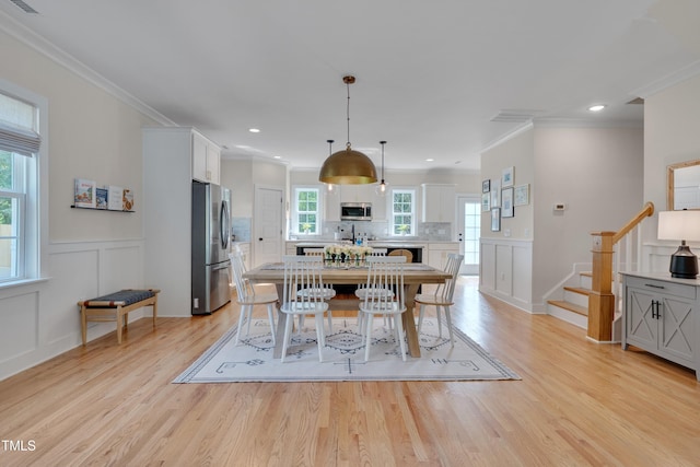 3003 University Dr, Durham, NC 27707 - dining room with stairs, light wood finished floors, a decorative wall, ornamental molding, and a wainscoted wall