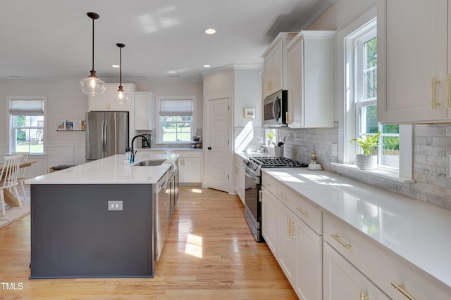 3003 University Dr, Durham, NC 27707 - kitchen with appliances with stainless steel finishes, a sink, ornamental molding, white cabinets, and a center island with sink