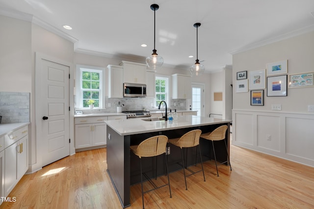 3003 University Dr, Durham, NC 27707 - kitchen with stainless steel microwave, crown molding, range, a sink, and white cabinets