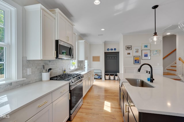 3003 University Dr, Durham, NC 27707 - kitchen featuring appliances with stainless steel finishes, a sink, backsplash, light countertops, and white cabinets