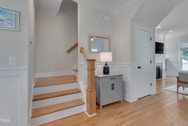 3003 University Dr, Durham, NC 27707 - stairs featuring ornamental molding, wood finished floors, a glass covered fireplace, a wainscoted wall, and a decorative wall