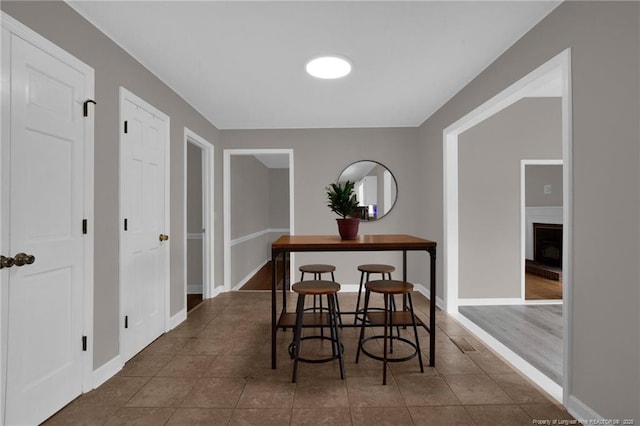 dining space with tile patterned flooring, a fireplace, and baseboards