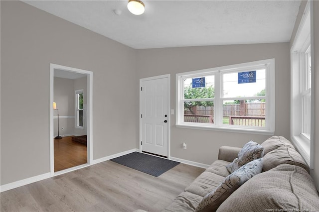 living room with vaulted ceiling, wood finished floors, and baseboards