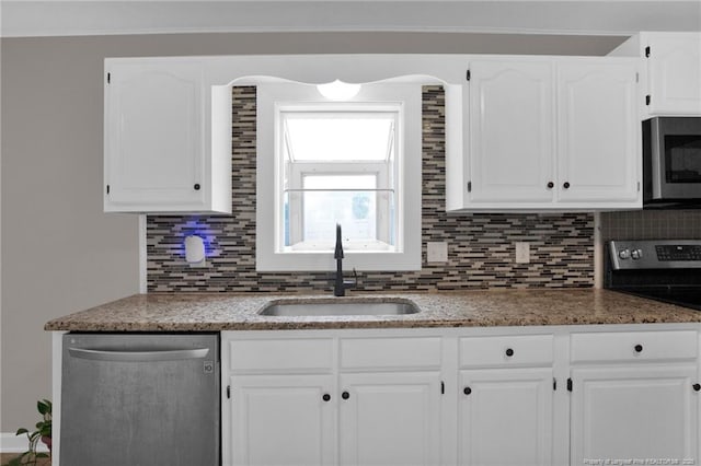 kitchen with appliances with stainless steel finishes, a sink, tasteful backsplash, white cabinetry, and light stone counters