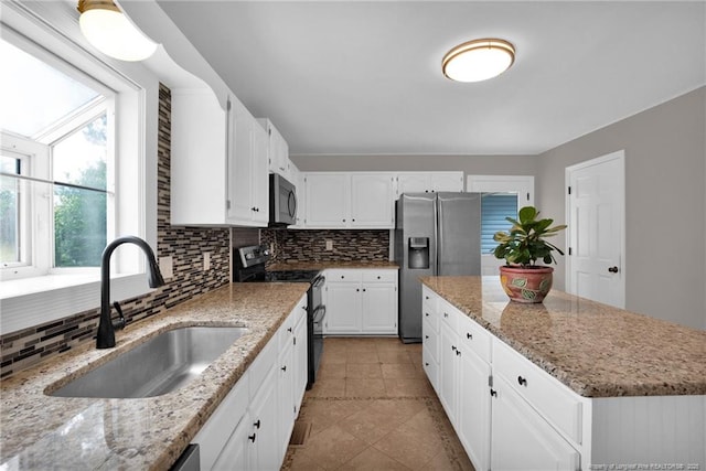 kitchen featuring appliances with stainless steel finishes, a sink, decorative backsplash, and a kitchen island