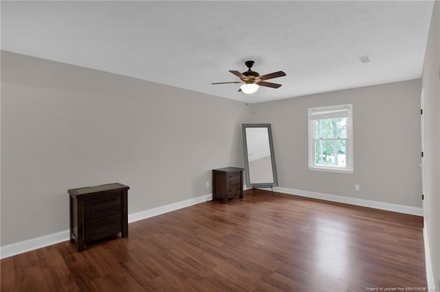 empty room featuring wood finished floors, a ceiling fan, and baseboards