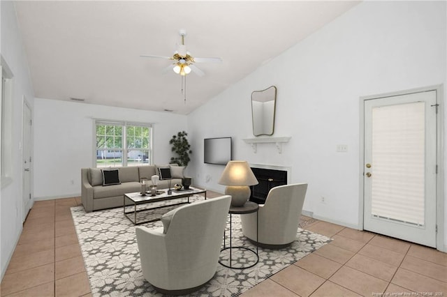 living room with lofted ceiling, a ceiling fan, light tile patterned floors, a fireplace, and baseboards