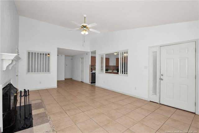 unfurnished living room featuring a ceiling fan, lofted ceiling, light tile patterned floors, and baseboards