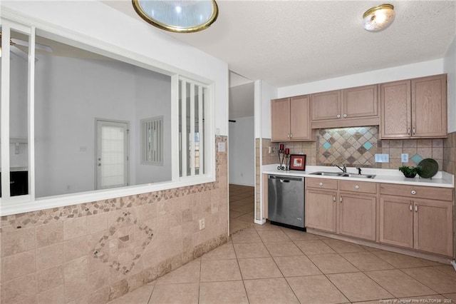 kitchen with stainless steel dishwasher, a sink, light countertops, light tile patterned floors, and tasteful backsplash