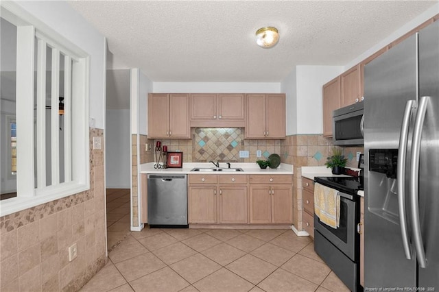 kitchen featuring stainless steel appliances, a sink, light countertops, a textured ceiling, and light tile patterned flooring