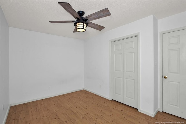 unfurnished bedroom with light wood-type flooring, baseboards, a closet, and a textured ceiling