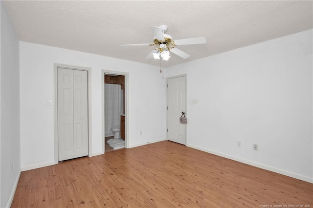 unfurnished bedroom with light wood finished floors, baseboards, ensuite bathroom, a textured ceiling, and ceiling fan