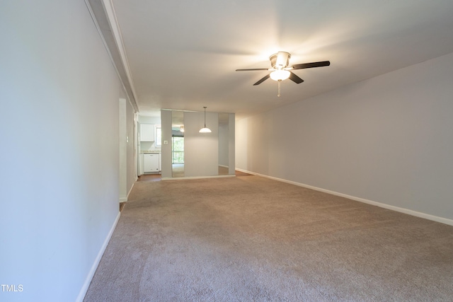 unfurnished room featuring ceiling fan, light colored carpet, and baseboards