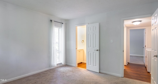 unfurnished bedroom with light carpet, baseboards, and ensuite bathroom