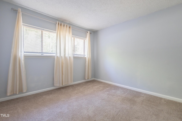 carpeted empty room with a textured ceiling and baseboards