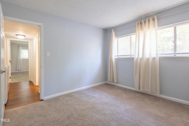 spare room with carpet, healthy amount of natural light, a textured ceiling, and baseboards