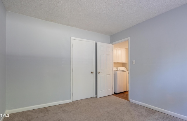 unfurnished bedroom with washer and dryer, carpet floors, baseboards, a textured ceiling, and a closet