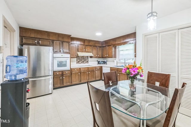 4407 Bromley Dr, Greensboro, NC 27406 - kitchen with white appliances, light countertops, under cabinet range hood, decorative light fixtures, and a sink