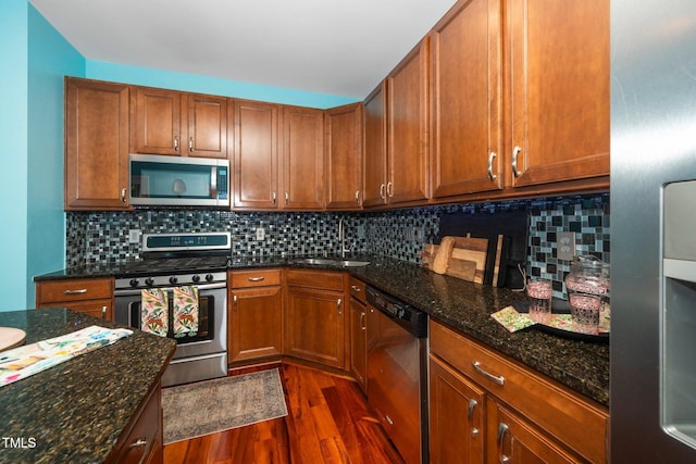3034 Winfred Dell Ln, Cary, NC 27511 - kitchen with appliances with stainless steel finishes, a sink, dark wood finished floors, dark stone countertops, and tasteful backsplash