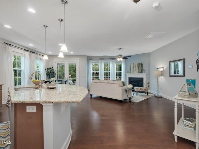 136 Shadow Hawk Dr, Durham, NC 27713 - kitchen with a sink, dark wood-style floors, baseboards, a glass covered fireplace, and light stone countertops
