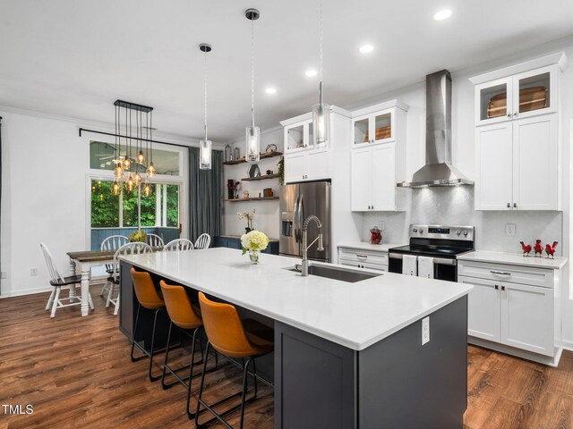 3400 Appling Way, Durham, NC 27703 - kitchen with wall chimney range hood, appliances with stainless steel finishes, an island with sink, a kitchen bar, and recessed lighting