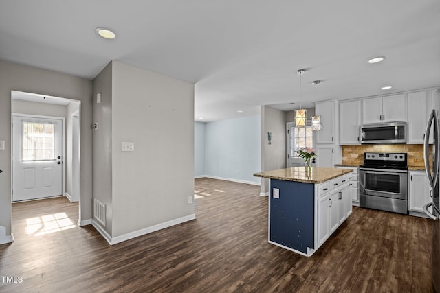 1195 Champion Dr, Cary, NC 27511 - kitchen with appliances with stainless steel finishes, a kitchen island, white cabinetry, light stone countertops, and dark wood-style flooring
